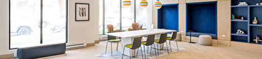 A conference room with a long table and chairs, a blue carpet, and a framed picture on the wall.