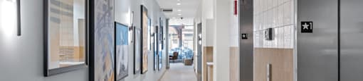 A hallway with elevators and artwork on the wall.