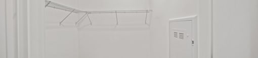 A white room with a wooden floor and a white cabinet.