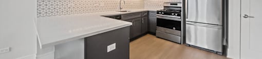 A kitchen with a white counter top and stainless steel appliances.