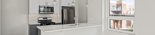 A kitchen with white cabinets and a large island with a sink.