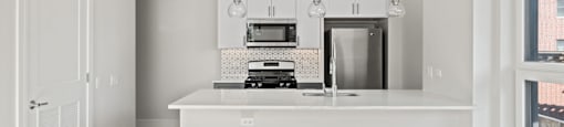 A white kitchen with a large island and pendant lights.