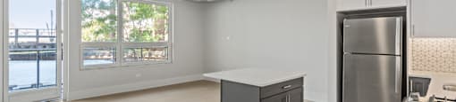 A kitchen with a stainless steel refrigerator and a black island.