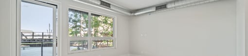 A room with a slanted ceiling and a door leading to a balcony.