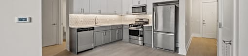 A modern kitchen with stainless steel appliances and wooden flooring.