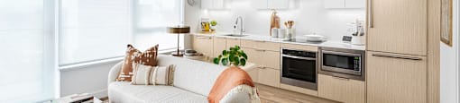 A modern kitchen with a white sofa and wooden floors.
