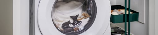 Two Whirlpool washing machines stacked on top of each other in a laundry room.