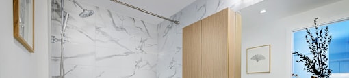 A bathroom with a marble patterned shower and a towel hanging on the railing.