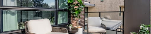 A patio with a chair, table, and potted plant.