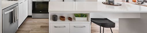 A modern kitchen with a white countertop and stainless steel appliances.