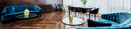A living room with a blue velvet sofa, a coffee table, and a chandelier.
