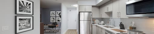 an open kitchen and living room with a stainless steel refrigerator