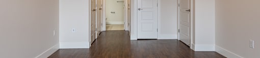 an empty living room with wood floors and white walls