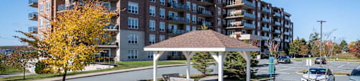 a park with a gazebo in front of an apartment building