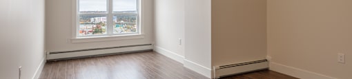 an empty living room with wood floors and a window
