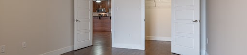 an empty living room with wooden floors and white doors