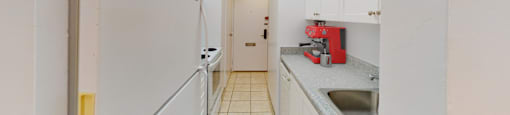 A kitchen with white cabinets and a red appliance.