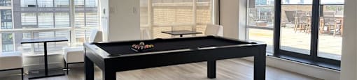 A pool table in a room with a view of the outside.