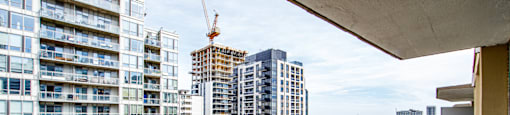 A balcony overlooks a cityscape with a crane in the distance.