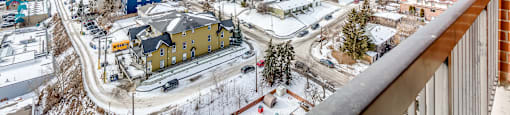 A view from a balcony overlooking a small town with buildings and roads.