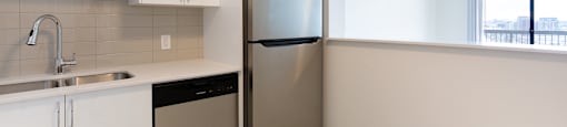 A kitchen with white cabinets and a stainless steel refrigerator.