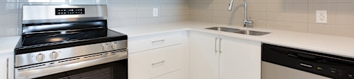 A modern kitchen with white cabinets and black appliances.