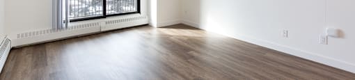 A room with a large window and wooden flooring.
