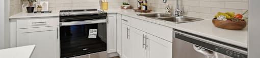 A modern kitchen with white cabinets and stainless steel appliances.