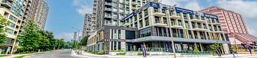 A tall building with a curved facade stands in front of two other buildings.