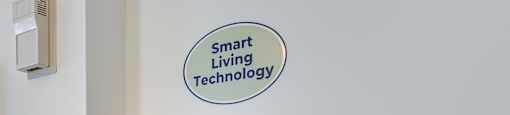 A wall-mounted smart TV with a sign above it that reads "Smart Living Technology".