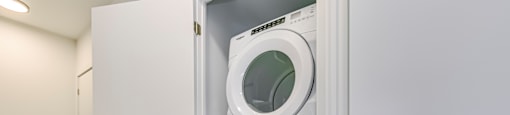 A white washing machine is in a white cabinet.