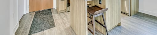A kitchen with a wooden bar stool in front of the counter.
