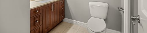 A white toilet sits in a bathroom with a sink and mirror.