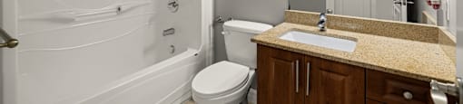 A bathroom with a white tub, sink, and toilet.