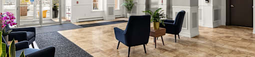 A spacious lobby with black chairs and a wooden floor.
