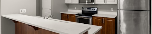 A kitchen with a stainless steel refrigerator, microwave, and oven.