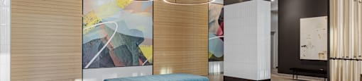 a lobby with a blue bench and a large painting on the wall