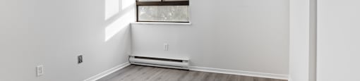 A room with a window and a radiator on the floor.