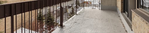 A balcony with a metal railing and snow on the ground.