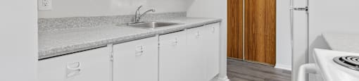 A kitchen with white cabinets and a wooden door.