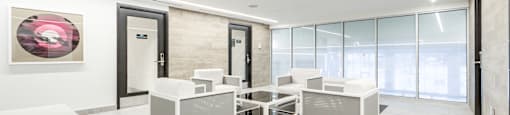 A modern office space with white furniture and a glass wall.
