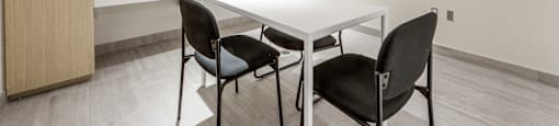 A conference room with a white table and four chairs.