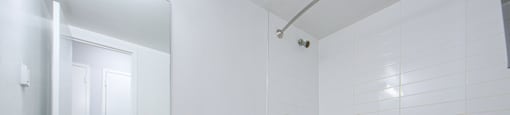 A white toilet sits in a bathroom with a white tub and a mirror.