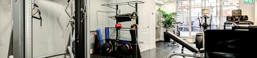 A gym with a variety of equipment including a squat rack, bench, and weights.