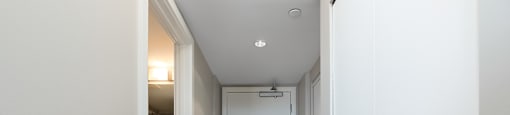 A hallway with a white door and a light on the ceiling.