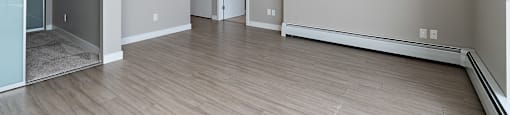 A spacious room with wooden flooring and white walls.