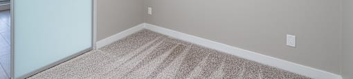 A room with a carpeted floor and a sliding glass door.