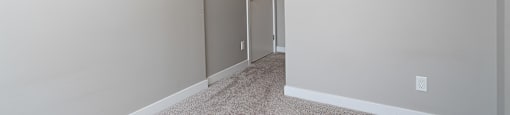 A room with a carpeted floor and a door.