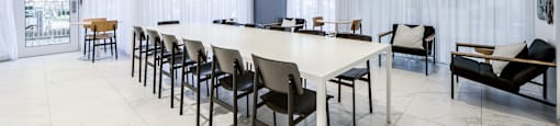 A white room with a long table and chairs.