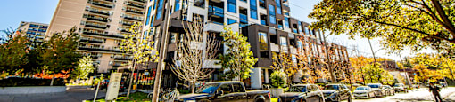 A tall blue and white building stands in the middle of a street lined with parked cars.